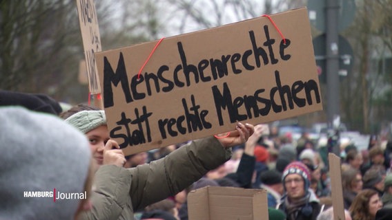 Auf einer Demonstration wird ein Schild mit der Aufschrift "Menschenrechte statt rechte Menschen" in die Höhe gehalten. © Screenshot 