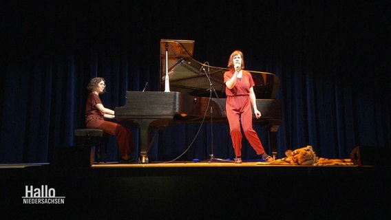 Zwei Frauen auf einer Bühne. Eine spielt am Flügel, die andere singt. © Screenshot 