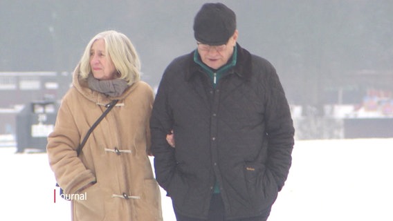 Ein älteres Paar spaziert durch einen winterlichen Park. © Screenshot 