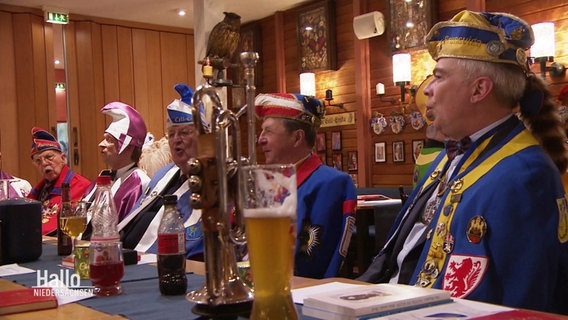 Männer in Karnevalsuniform sitzen singend an einem Tisch. © Screenshot 