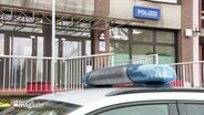 Im Vordergrund das Blaulicht eines Polizeiwagens, im Hintergrund das Schild "Polizei" einer Polizeistation. © Screenshot 