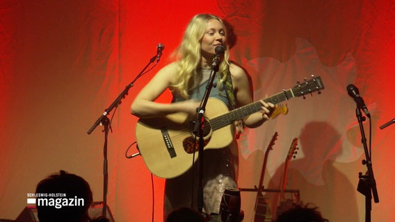 Die Singer-Songwriterin Catt auf der Bühne, sie spielt Gitarre und singt. © Screenshot 