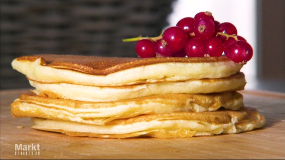 Mehrere Pancakes übereinander auf einem Stapel, obenauf liegt ein Zweig mit roten Johannisbeeren. © Screenshot 
