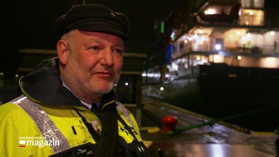 Der Lotse Jürgen Marth steht vor einem Boot. © Screenshot 