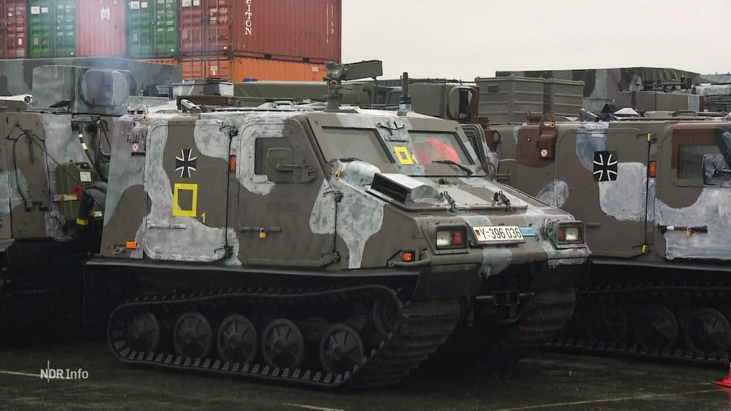 Militärfahrzeuge der Bundeswehr mit Tarnmuster. Im Hintergrund stehen Container.
