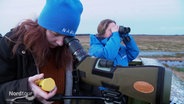 Zwei Frauen in Kleidung des NABU beobachten Vögel durch Ferngläser. © Screenshot 