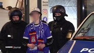 Ein HSV-Fan wird von zwei Polizisten begleitet. © Screenshot 