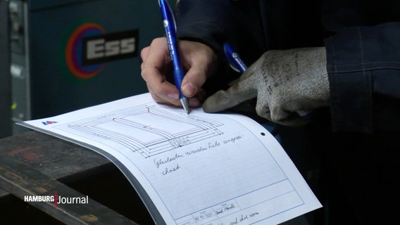 Ein Auszubildender notiert Maße eines Werkstücks auf einem Blatt Papier. © Screenshot 