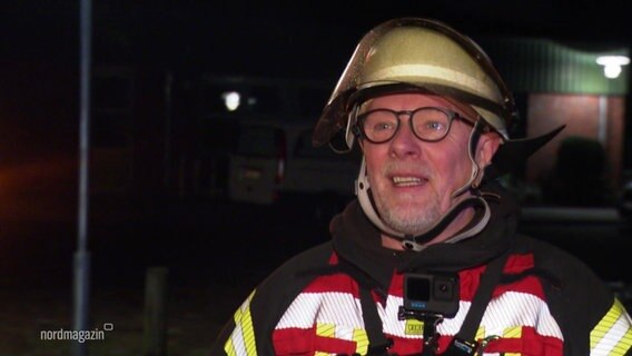 Ein Mann mit Brille und Dreitagbart in Feuerwehrkleidung blickt in die Kamera. © Screenshot 