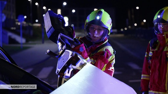 Eine Person in Feuerwehrkleidung schneidet mit einem großen Gerät ein Auto auf © Screenshot 