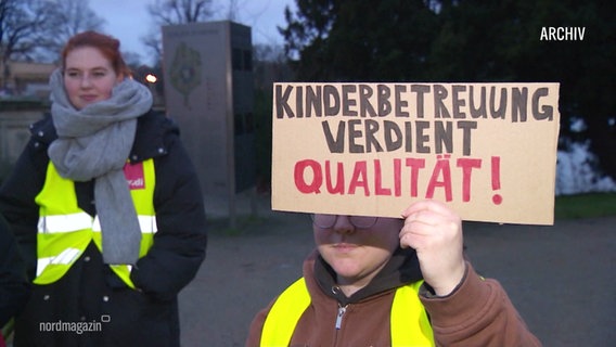 Eine Streikende hält ein Schild mit der Aufschrift "Kinderbetreuung verdient Qualität". © Screenshot 