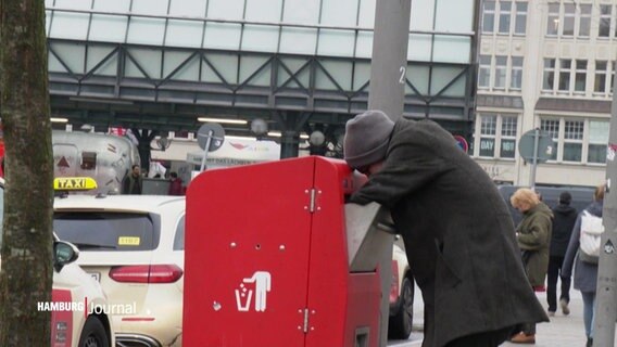 Eine Person durchsucht einen Mülleimer nach Pfand. © Screenshot 