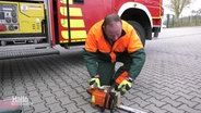 Ein Feuerwehrmann testet eine Kettensäge. © Screenshot 