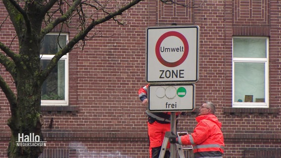Mitarbeiter des Straßenamts schrauben ein Schild ab. © Screenshot 