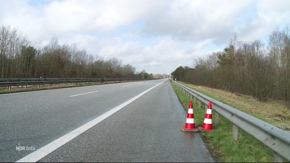 Zwei rote Absperrhütchen stehen am Rand der Autobahn. © Screenshot 