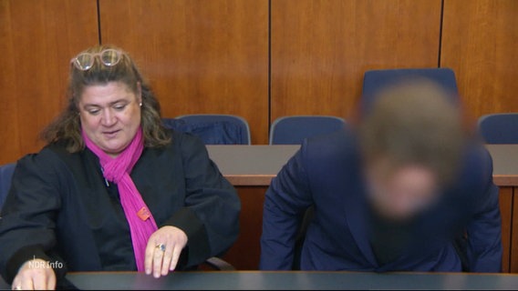 Der unkenntlich gemachte Angeklagte nimmt im Gericht neben seiner Anwältin Platz. © Screenshot 