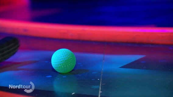 Ein Golfball liegt im Neonlicht. © Screenshot 