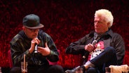 Jan Delay und Diggen sitzen auf Sesseln auf der Bühne des Schmidt Theaters. © Screenshot 