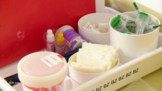 Verschiedene medizinische Utensilien und Medikamente sind in Plastikbehältnissen sortiert. © Screenshot 