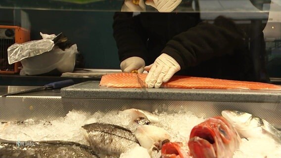 An einer Fischverkaufstheke wird ein Lachs geschnitten. © Screenshot 
