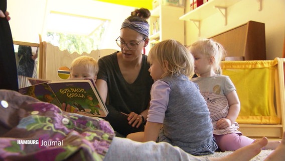 Eine Frau schaut mit drei Kleinkindern ein Buch an. © Screenshot 