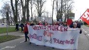 Ein Demo-Zug läuft eine Straße entlang. © Screenshot 