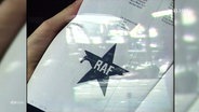 Jemand hät ein Dokument mit dem RAF-Symbol in der Hand. © Screenshot 