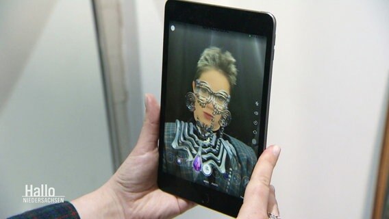 Eine Frau betrachtet sich in einem Smartfon. © Screenshot 