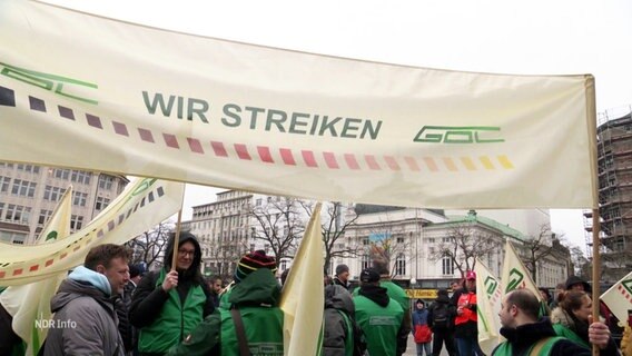 Streikende der GDL halten ein großes Banner mit der Aufschrift "Wir streiken". © Screenshot 