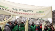 Streikende der GDL halten ein großes Banner mit der Aufschrift "Wir streiken". © Screenshot 