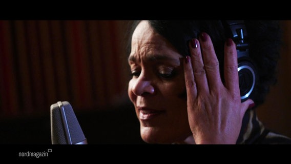 Eine Sängerin singt in ein Mikrofon. © Screenshot 