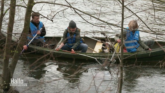 Drei Personen in einem Kanu sammeln Müll aus einem Fluss. © Screenshot 