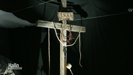 Ein nachgebautes hölzernes Kreuz mit einer Dornenkrohne, dramatisch beleuchtet. © Screenshot 