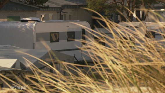 Campingwagen stehen hinter einer Düne. © Screenshot 