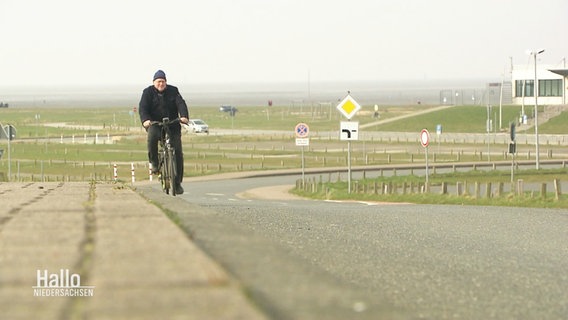 Eine Person in dunkler Kleidung fährt auf dem Weser-Radweg Fahrrad. © Screenshot 