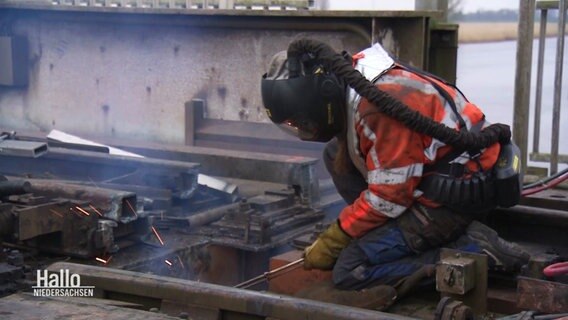Ein Arbeiter in Sicherheitsbekleidung arbeitet am Abriss der zerstörten Brücke. © Screenshot 