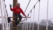 Ein Mann balanciert im Klettergarten über ein Drahtseil. © Screenshot 