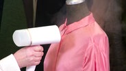 Eine rosafarbene Bluse auf einer Büste wird mit einer Dampfbürste geglättet. © Screenshot 