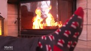 Jemand wärmt sich die Füße am Kaminfeuer. © Screenshot 