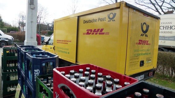 Ein DHL-Transporter steht hinter Getränke-Kisten. © Screenshot 