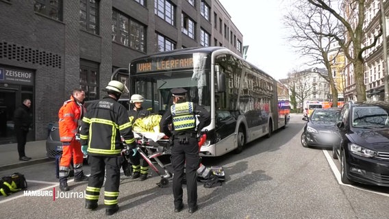 Mehrere Polizisten und Rettungskräfte stehen vor einem verunfallten Bus und versorgen einen Verletzten. © Screenshot 