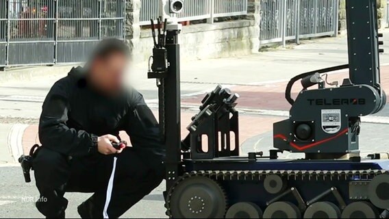 Einn Polizist arbeitet an einem Sprengroboter in Lüneburg © Screenshot 