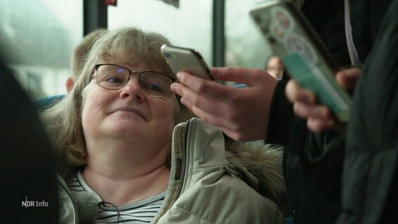 Eine Frau sitzt in einem überfüllten Bus. © Screenshot 