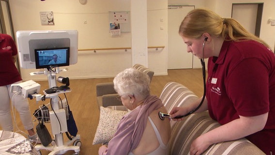 Eine Pflegekraft misst die Vitalwerte einer Patientin, welche über das Internet direkt an deren zugeschalteten Hausarzt weitergeleitet werden und besprochen werden können. © Screenshot 