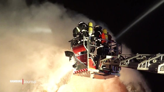 Einsatzkräfte der Feuerwehr löschen ein in Brand geratenes Reetdachhaus. © Screenshot 