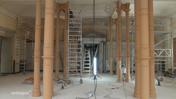 Ein Raum mit Säulen in dem große Gerüste und eine helle Baustrahler einer Baustelle stehen. © Screenshot 
