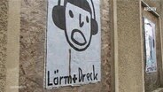 Ein Poster mit der Abbildung eines Kopfes der Kopfhörer trägt und der Unterschrift "Lärm plus Dreck". © Screenshot 