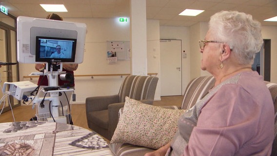 Eine ältere Dame ist über einen Monitor mit einem Arzt verbunden. © Screenshot 