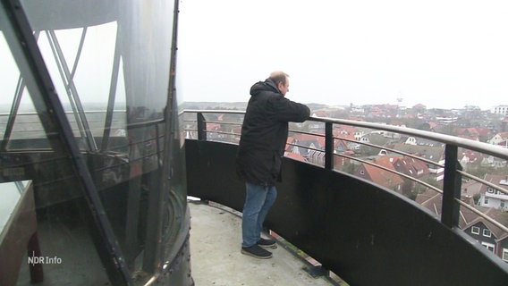 Ein Mann steht auf einem Leuchtturm-Balkon an der Brüstung und sieht in die Ferne. © Screenshot 