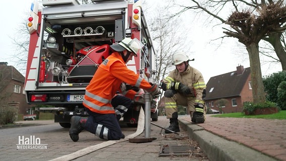 Mitglieder einer Freiwilligen Feuerwehr schließen einen Wasserschlauch an einen Hydranten. © Screenshot 